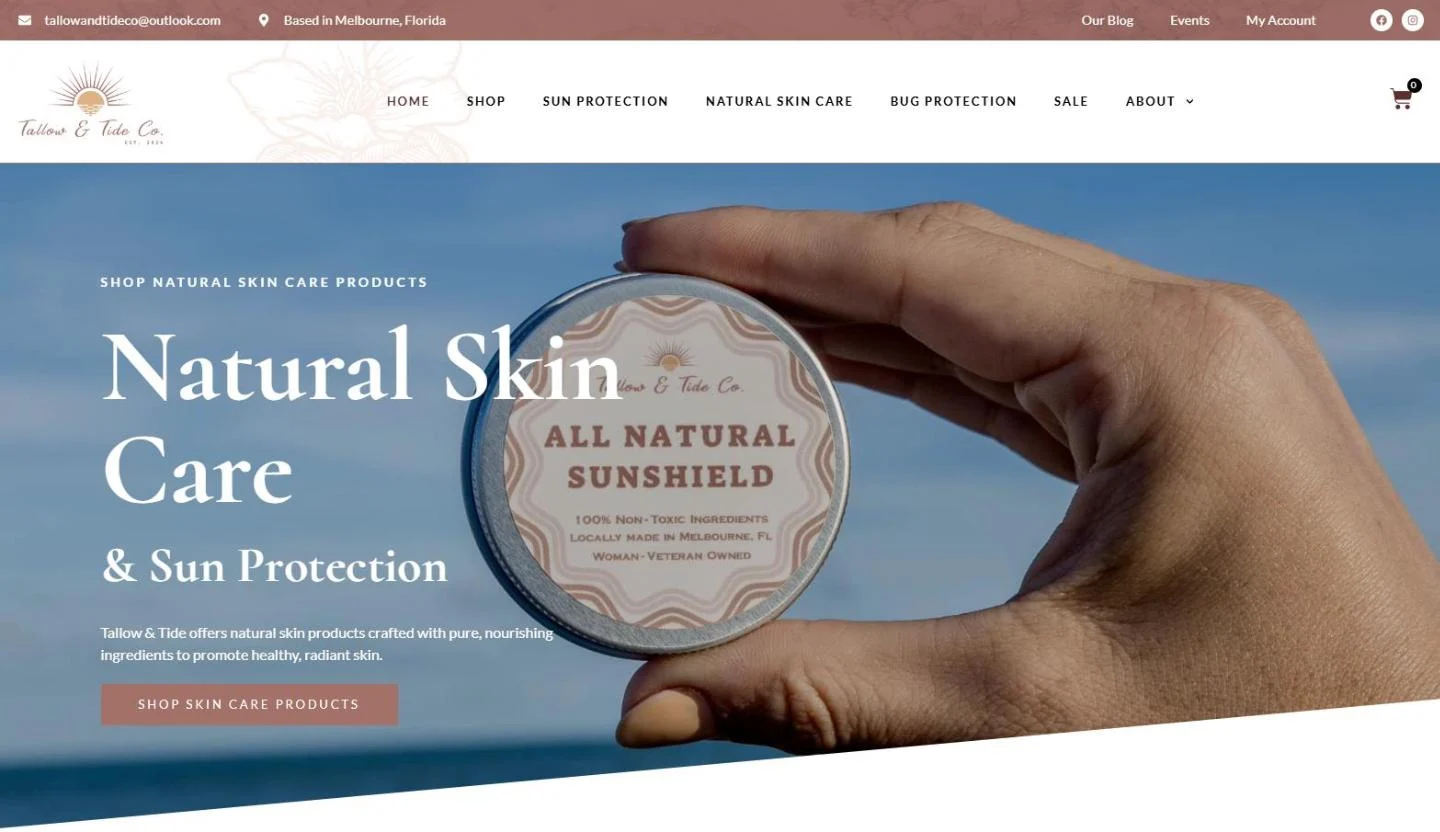 The Tallow and Tide Co. homepage: a hand holding a round tin of All Natural Sunshield against a blue ocean sky, beside the headline Natural Skin Care and Sun Protection and a Shop skin care products button, under a navigation bar with Shop, Sun Protection, Natural Skin Care, Bug Protection and Sale